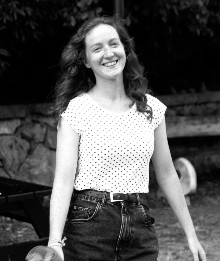 Happy woman walks with a plastic bag, smiling on a sunny day.