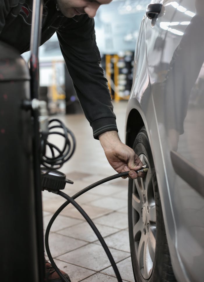 Mechanic adjusting tire pressure of a vehicle in an indoor automotive service center.